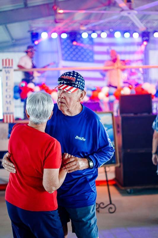 Two people dancing at a lively indoor event with colorful stage lights in the background