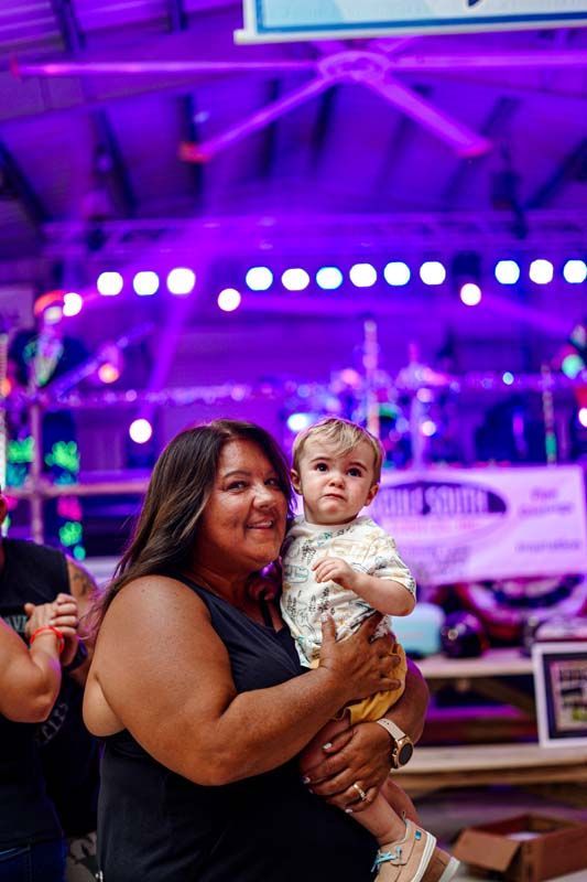 A woman is holding a baby in her arms at a concert.