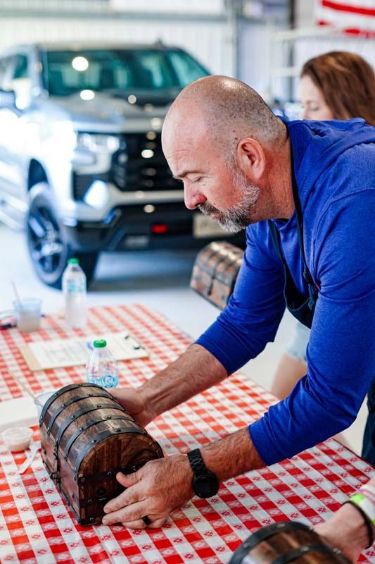 Man in blue shirt carefully examining a wooden object on a checkered table in a showroom