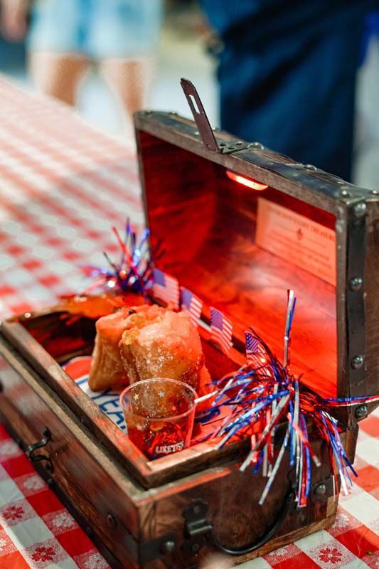 Open treasure chest with a roast chicken and red-blue sparklers on a checkered tablecloth
