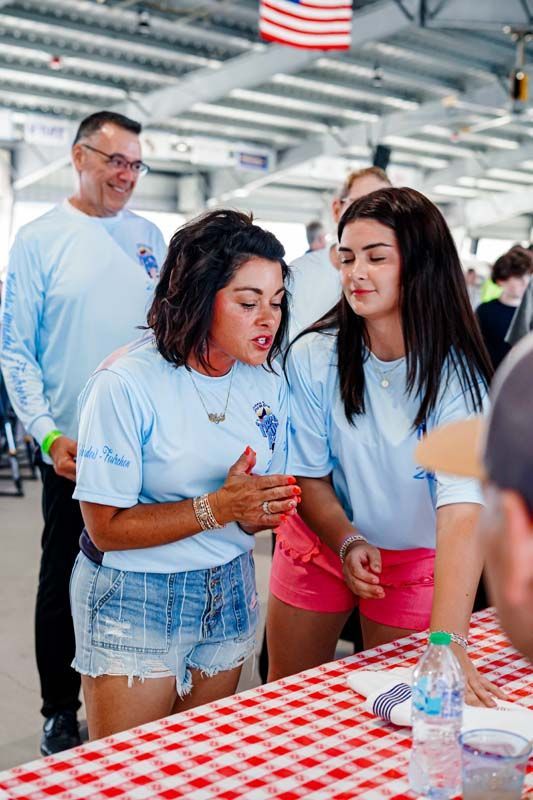 People in light blue shirts and red shorts at a checkered table in a bright indoor venue