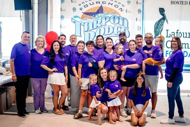 Group of people in purple shirts posing at an event booth with a “Top 10 Digs” sign