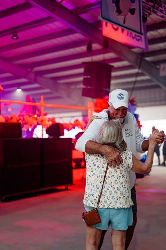 Two people hugging in a neon-lit indoor venue with pink and red lighting