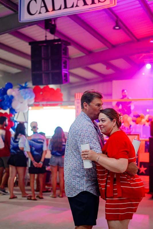 Two people dancing in a pink-lit hall during a lively indoor event