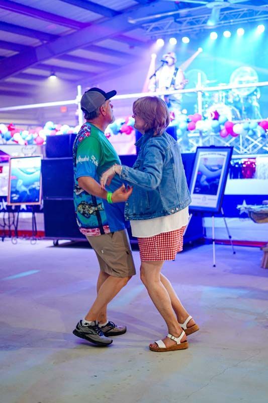 Two people dancing together in a brightly lit arcade or entertainment venue