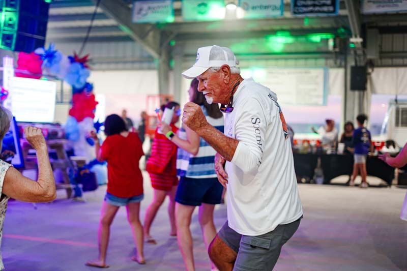 Man in white cap dancing at a colorful indoor party with other people in the background