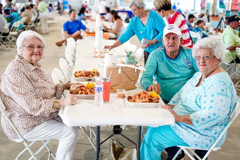 A group of elderly people are sitting at a table eating food.