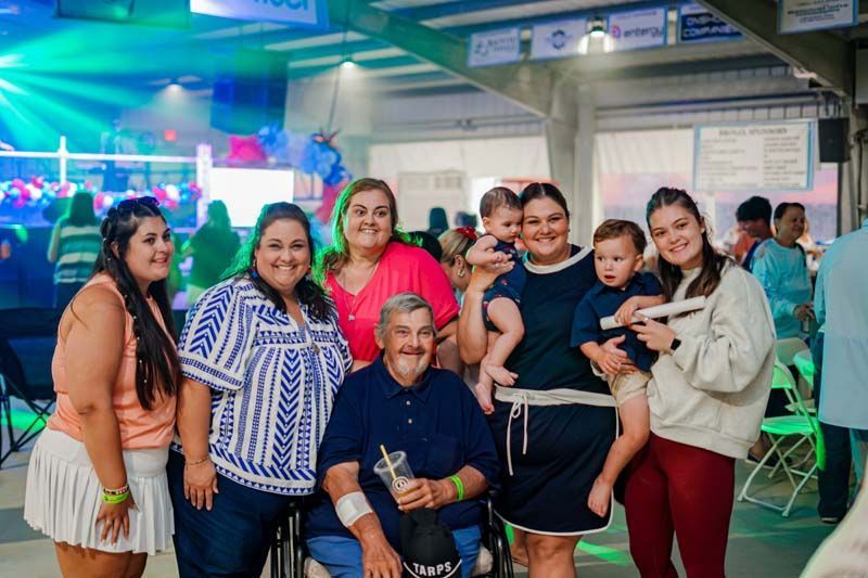 Group of people smiling at a lively indoor event, posing together under colorful lights