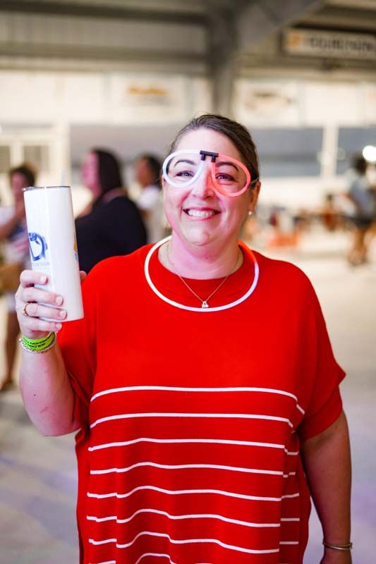 Smiling person in a red striped shirt holding a white bottle in a bright indoor setting