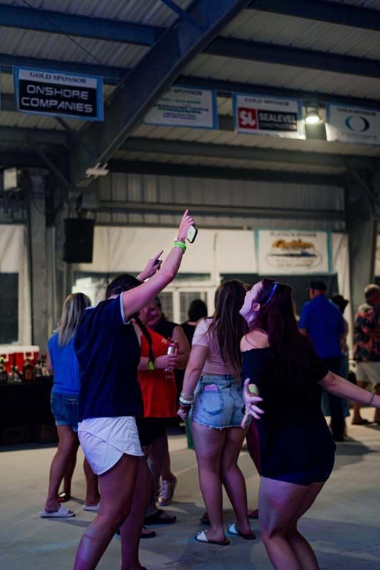 Group of people dancing and holding up drinks in a covered outdoor venue at night