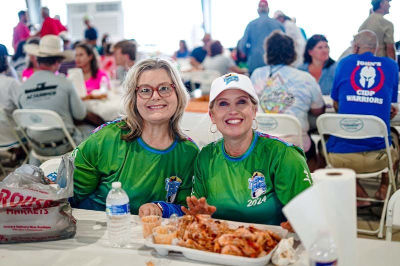 Two women are sitting at a table with a plate of food.