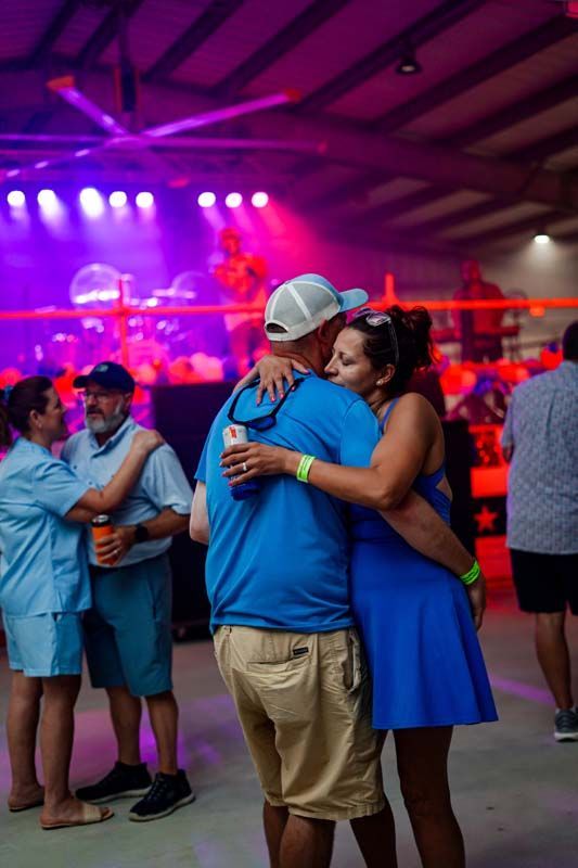 Couple embracing on a crowded concert floor under purple stage lights