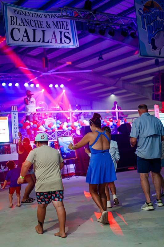 People dancing in a neon-lit venue under a sign reading “Blanche & Mike Calais”