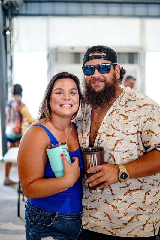 A man and a woman are posing for a picture while holding drinks.