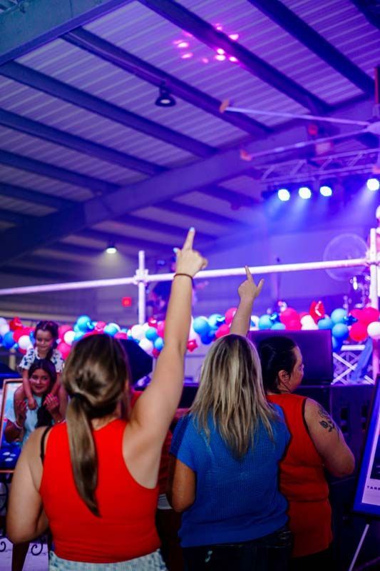 Crowd at concert with raised hands under purple stage lights in an indoor venue