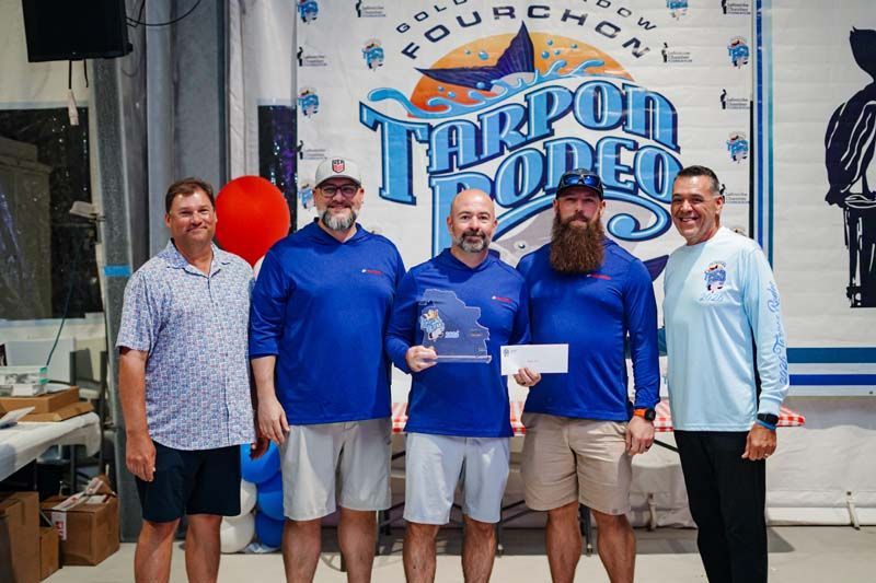 Five men stand holding a check in front of a 4th Quarter Taboo Taco banner.