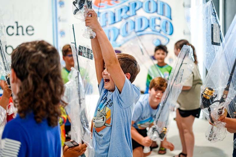A group of children are holding swords in a room.