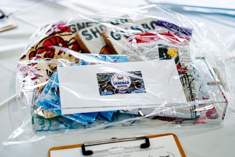 Plastic bag filled with assorted packaged items, including a white envelope with a circular logo.