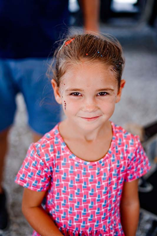 Smiling child in a pink patterned shirt standing indoors