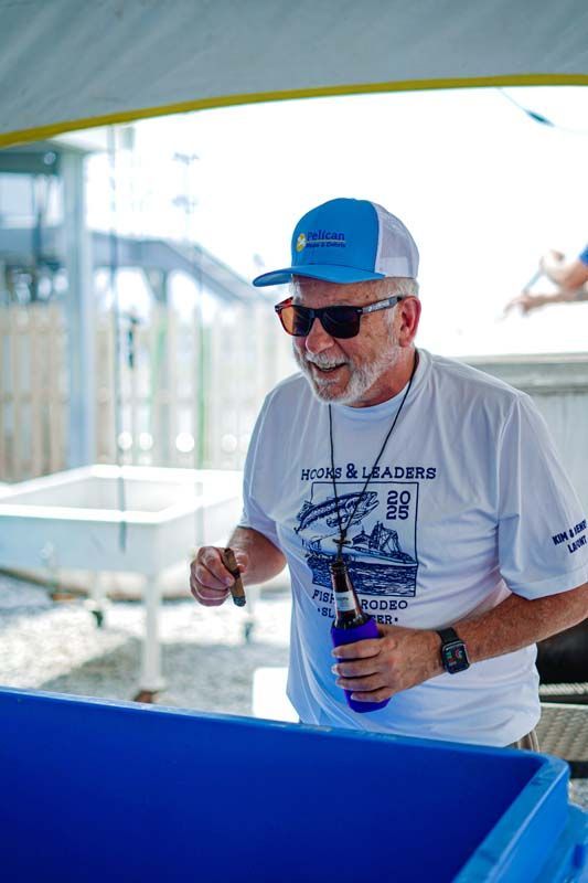 Man in blue cap and sunglasses holding a bottle beside a blue container at an outdoor event