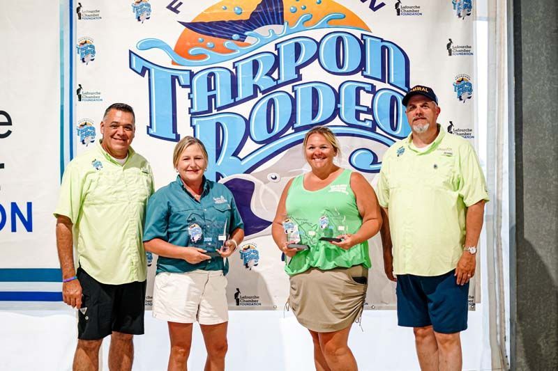 A group of people standing in front of a tarpon rodeo sign