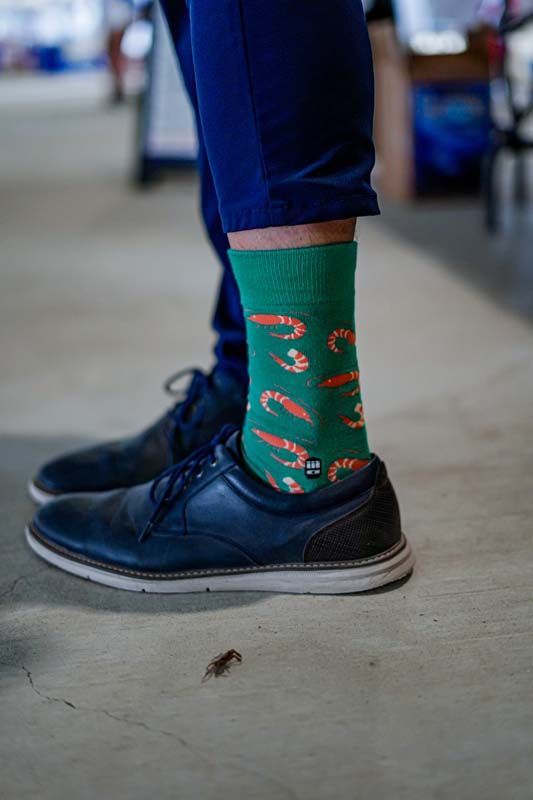 Close-up of blue shoe and green patterned sock on a concrete floor