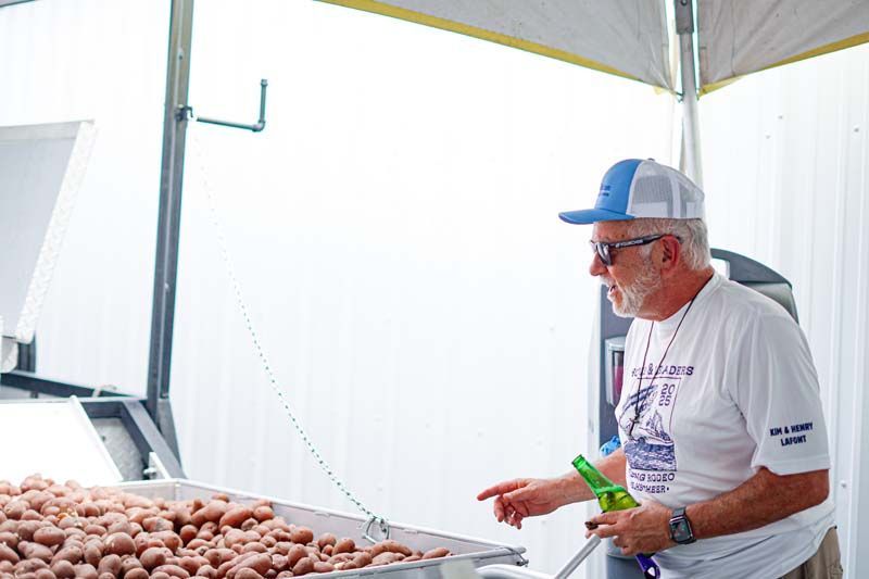 Man in a blue cap and glasses serving food at an outdoor market stall