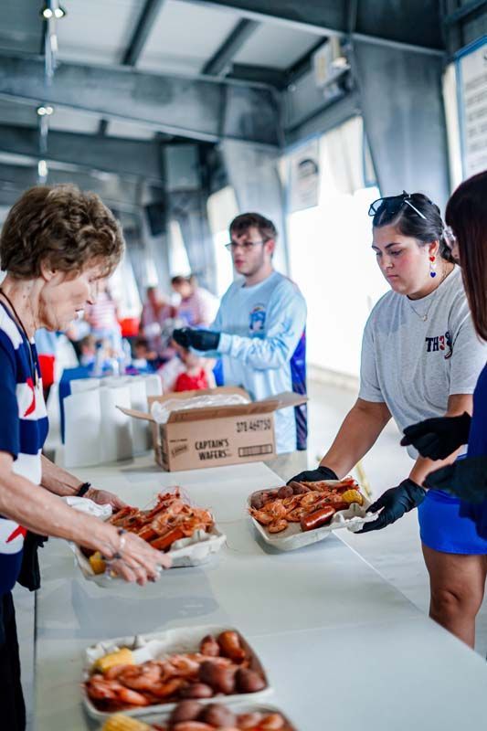 Volunteers serving roasted meat at a long table in a bright indoor hall