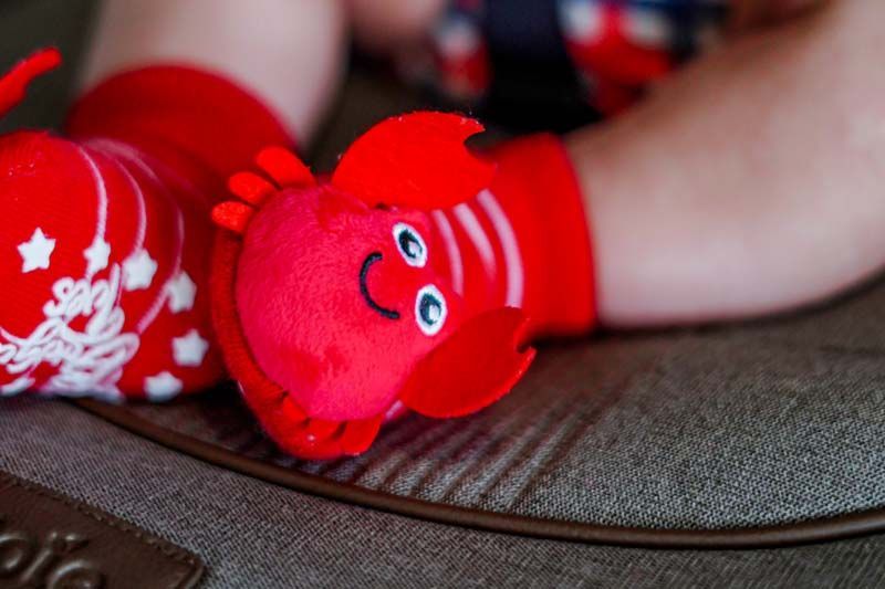 Red holiday socks with smiling faces on a couch, with a person’s arm in the background
