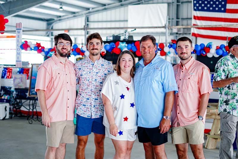 Five people posing in a decorated warehouse with red, white, and blue bunting and flags