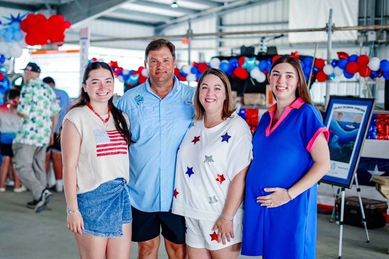Four people posing together at a red, white, and blue decorated event booth