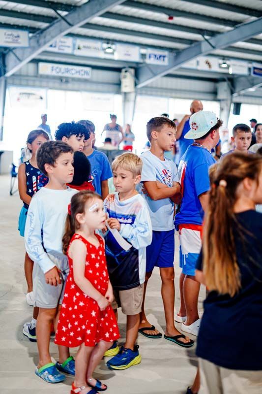 Children gathered indoors at a public event, waiting in line near a doorway.