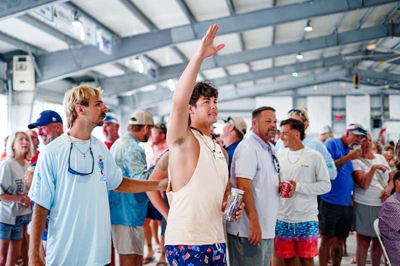 Crowd of fans standing in a stadium, one man raising his arm amid a lively indoor event