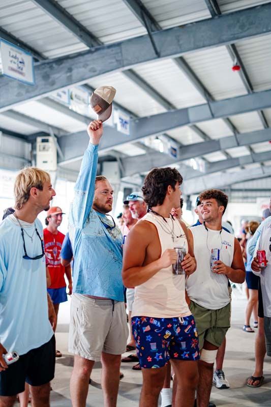 Group of people in a gym, one lifting a trophy while others watch and clap