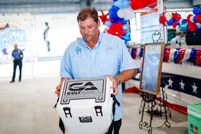 Man holding a folded white rally towel with black text at a patriotic indoor event