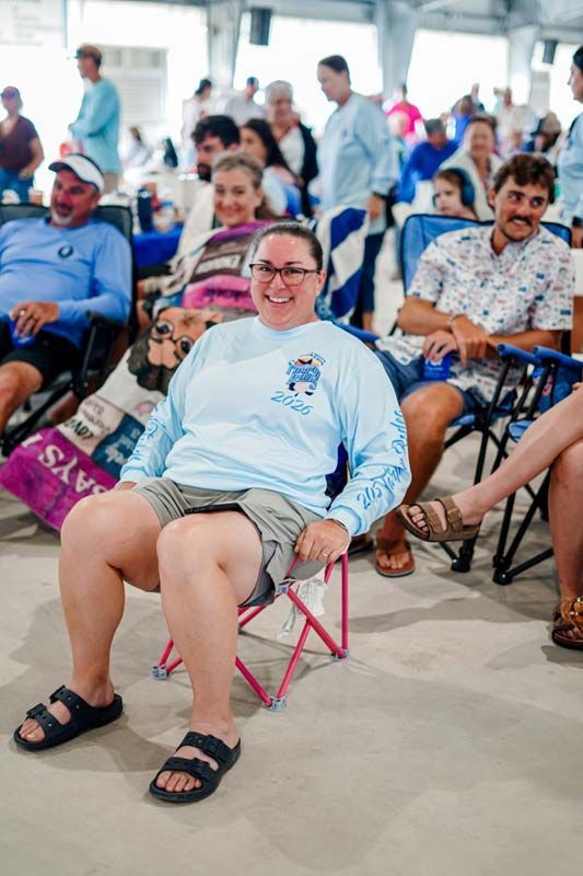People sitting in wheelchairs and beach chairs at an outdoor gathering, smiling and relaxed.