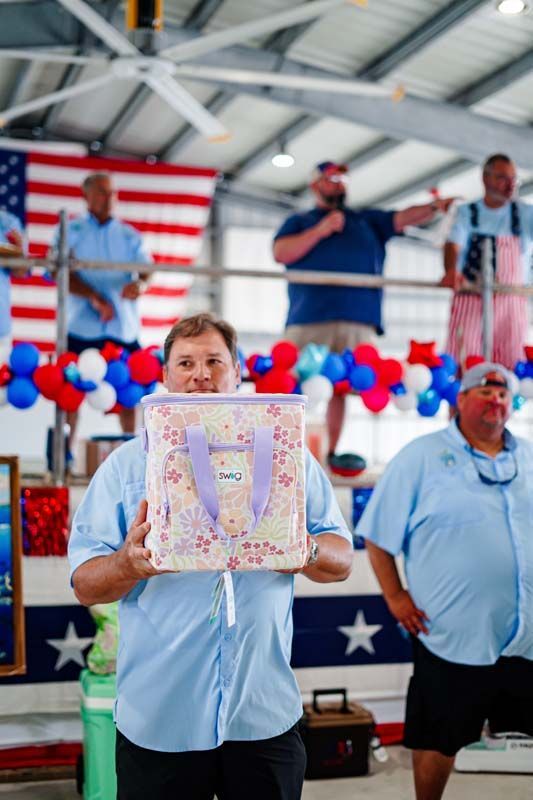 Person holding a framed artwork on a patriotic stage with red, white, and blue decorations