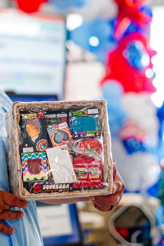 Handmade colorful gift basket held up in a shop, with assorted packaged items visible inside