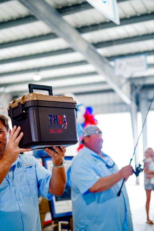 People in blue uniforms carry equipment in a bright industrial facility