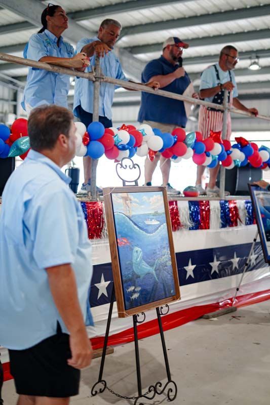 Men standing on a decorated platform with red, white, and blue bunting, addressing a crowd at an event