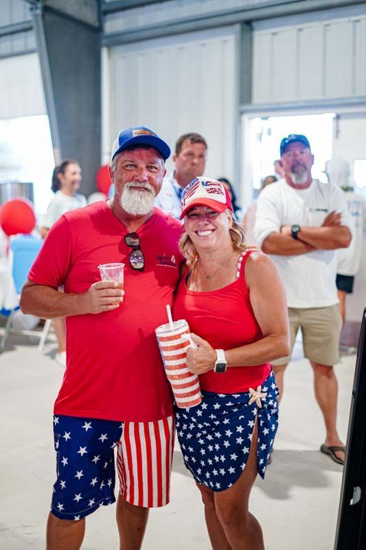 Two people in red, white, and blue outfits holding drinks at a casual indoor event