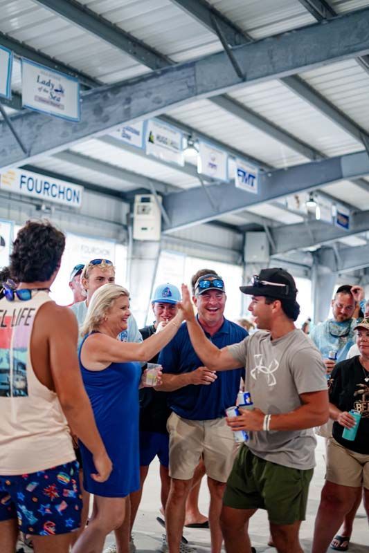 People giving high-fives under a covered venue, with one person in a blue hard hat smiling.