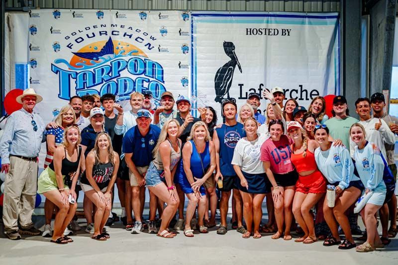 Group of athletes posing at an indoor event with a large “Tarpon Rodeo” banner in the background