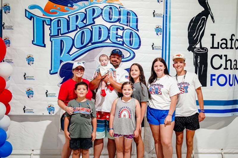Group of children posing in front of a Tarpon Rodeo sign at a community event