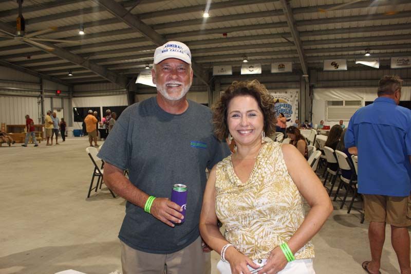 A man and a woman are posing for a picture in a large room.