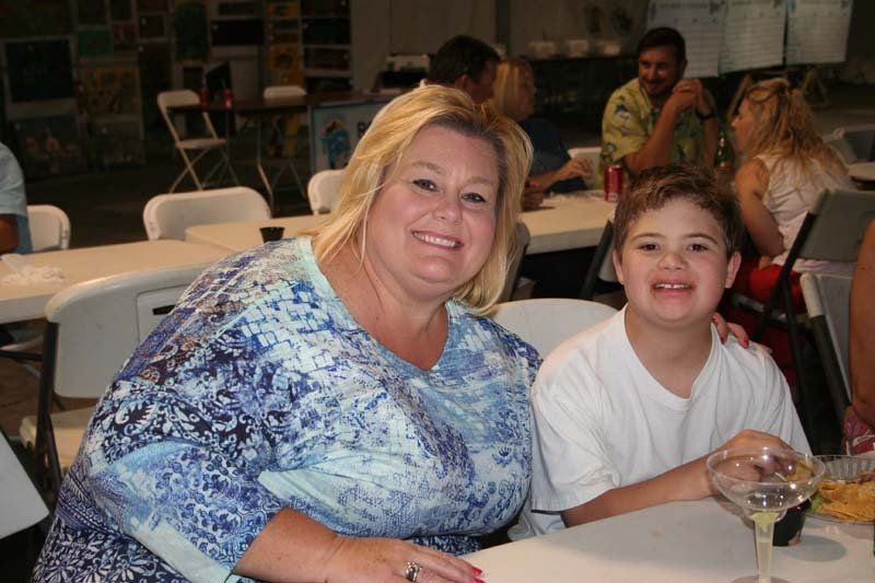 A woman and a boy are posing for a picture while sitting at a table.