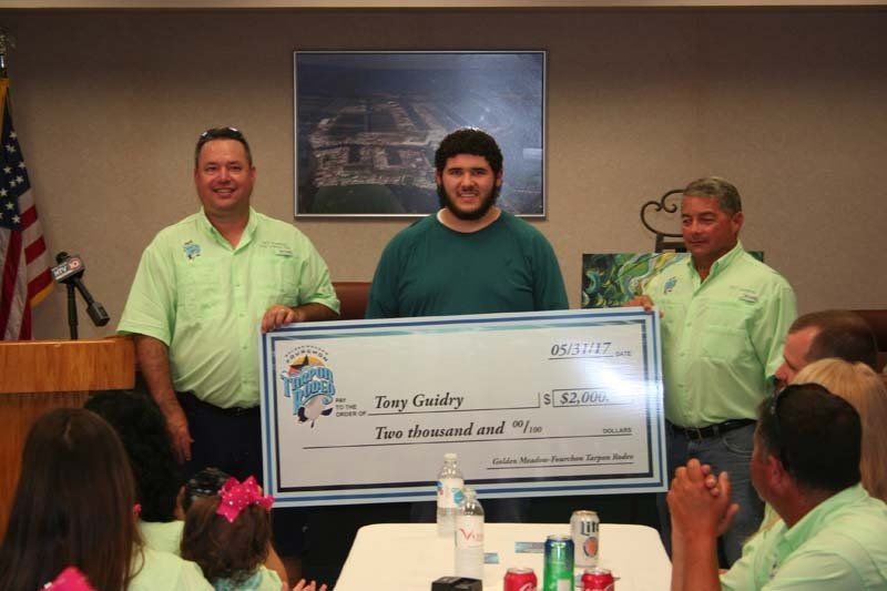 A man in a green shirt is holding a large cheque for two thousand dollars
