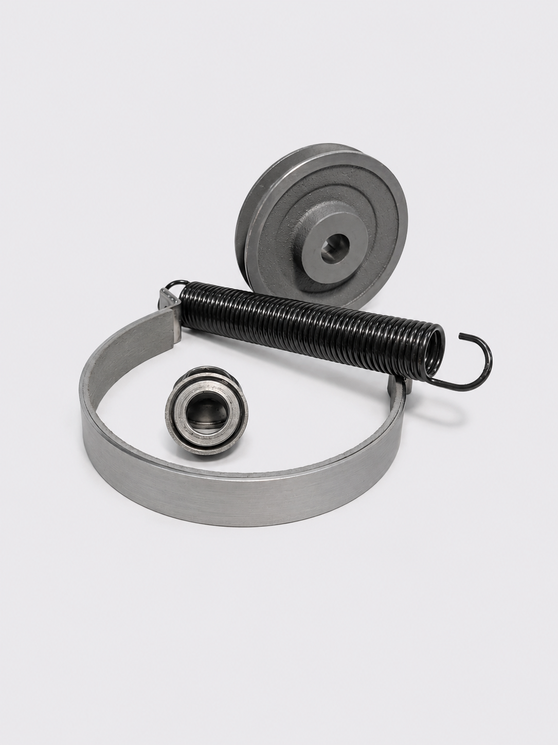 Metal spring-loaded mechanical parts on a white background, including a coil spring, wheel, and ring-shaped piece
