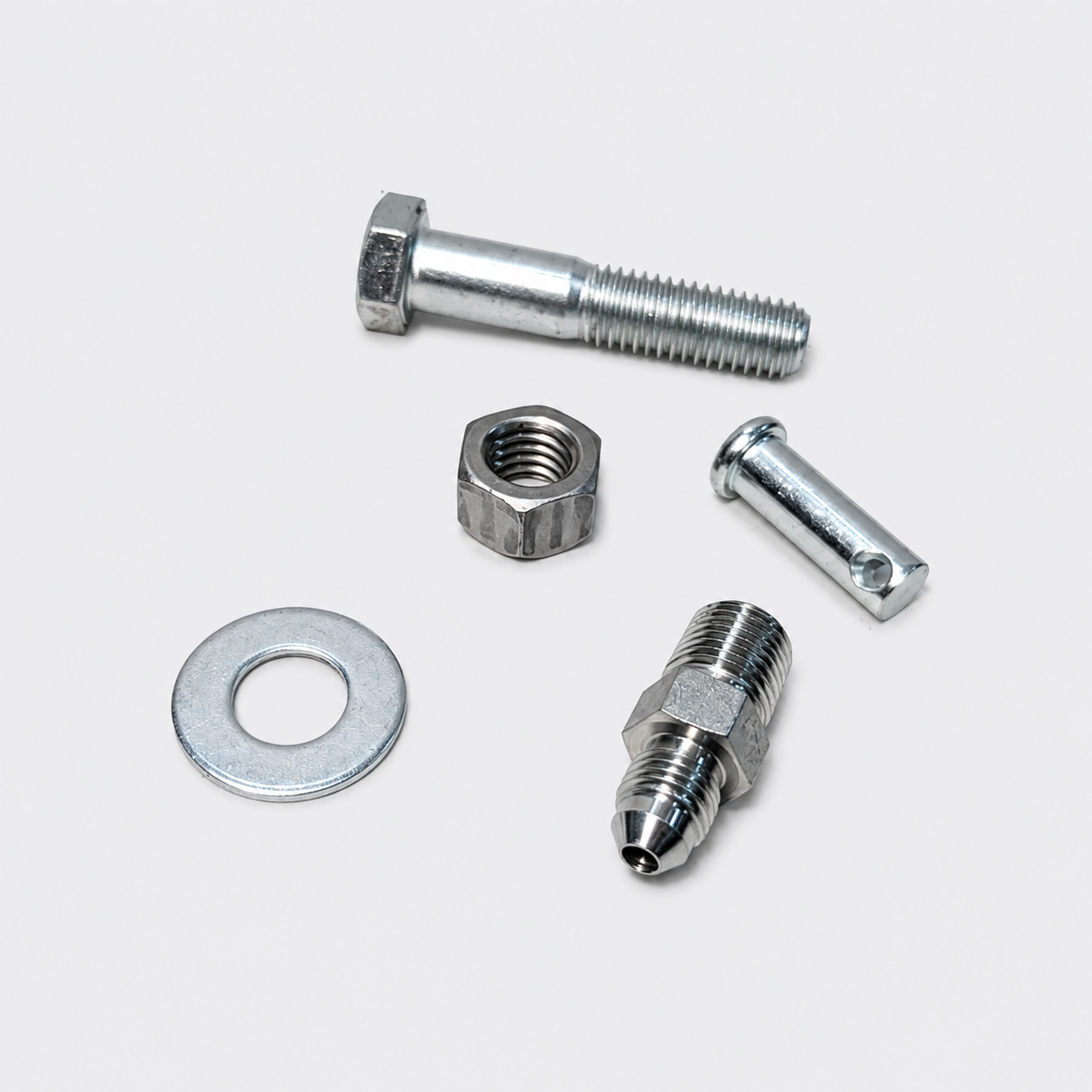 Assorted silver metal fasteners: bolt, nut, washer, pin, and threaded fitting on white background