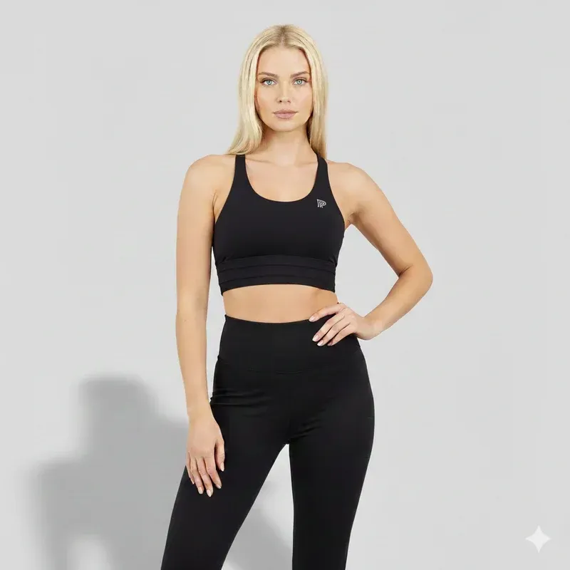 Woman in black athletic wear posing against a light gray studio background